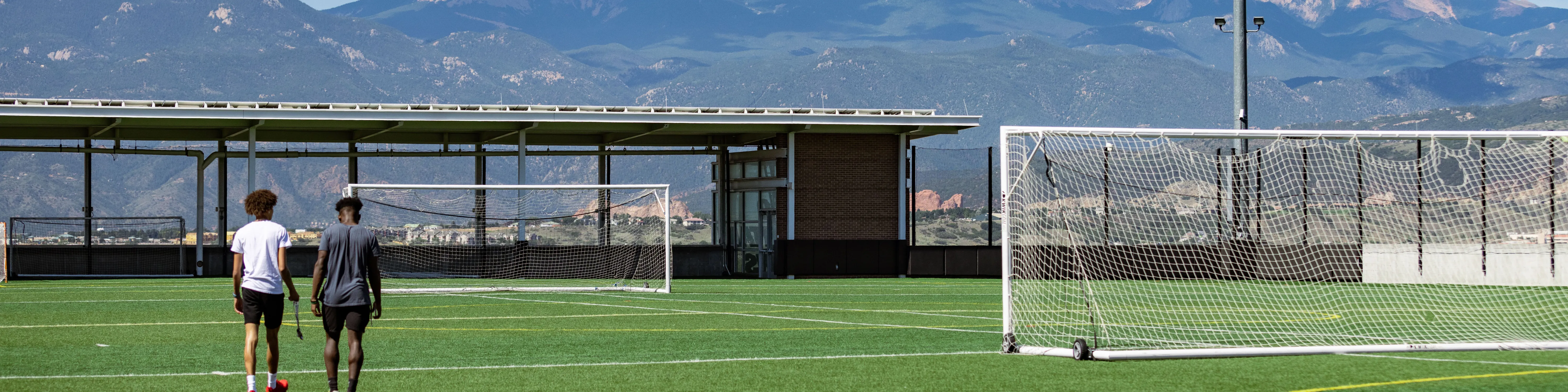 students walking on the soccer field, facing the mountains